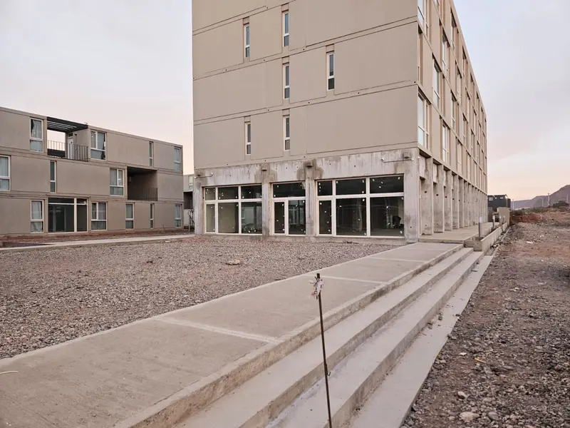 Finished concrete sidewalks and curbs beside residential blocks in Añelo
