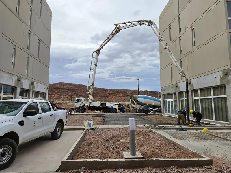 Concrete boom pump and mixer truck pouring between two buildings
