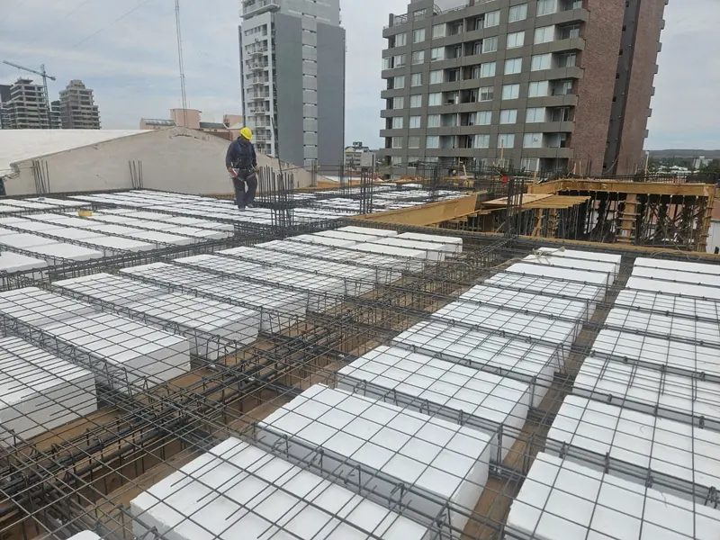 Losa alivianada con casetones y armadura de hierro, con operario y torres de la ciudad al fondo
