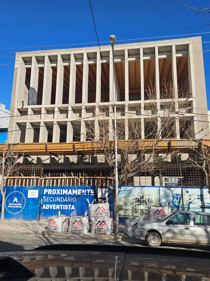 Completed school facade in exposed concrete with vertical louvres and secondary school sign