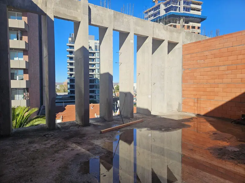 Columnas de hormigón visto y muro de ladrillo a la vista bajo cielo despejado