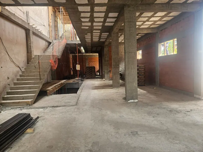 Interior en obra con escalera de hormigón, losa nervurada a la vista y muro de ladrillo