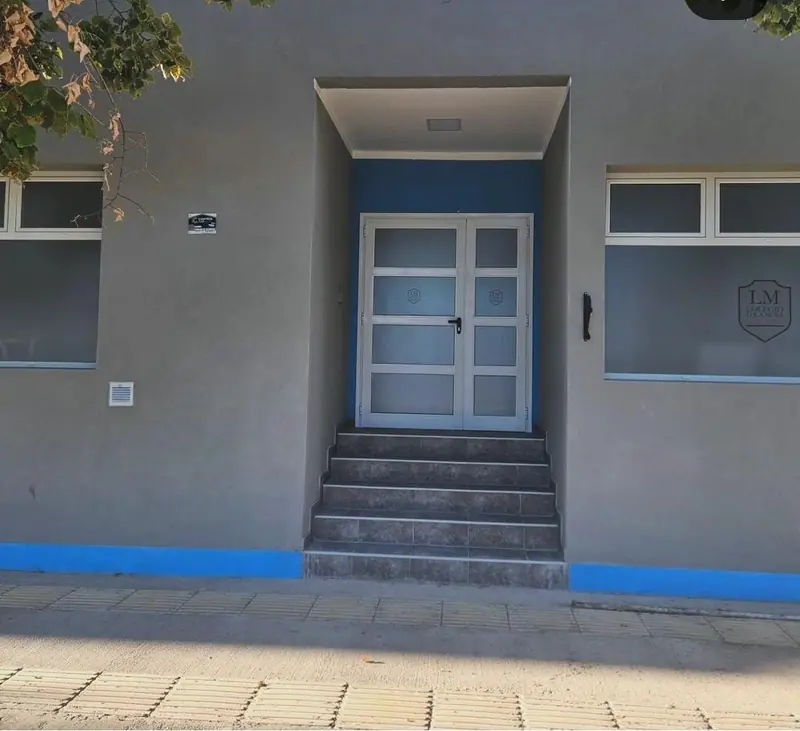 Acceso principal del colegio con escalera de hormigón y puerta doble de aluminio y vidrio