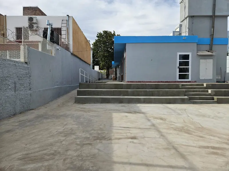 Patio de hormigón terminado con escalones, baranda metálica y módulo de aulas