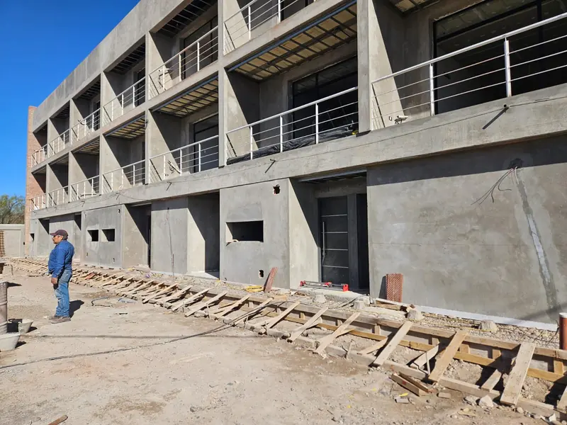 Front elevation under construction with exposed concrete structure, metal balcony railings and stacked planks
