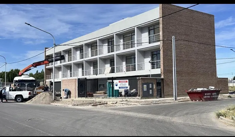 Housing block in the final stage with a truck-mounted crane working and exposed brickwork side wall