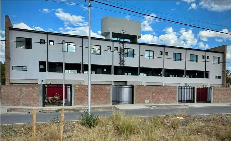 Completed facade of the housing complex with water storage tank on the roof and entrance gates