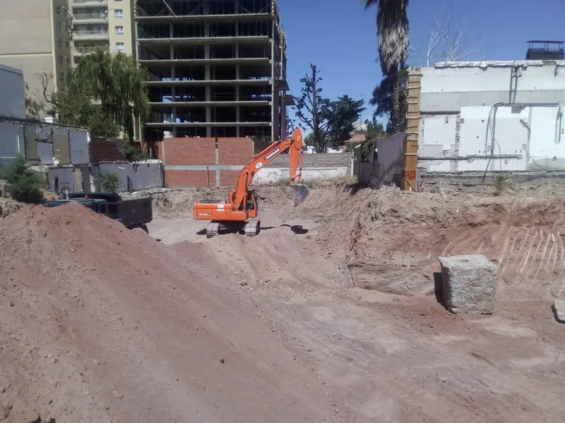 Excavator moving soil on the site with the tower under construction behind