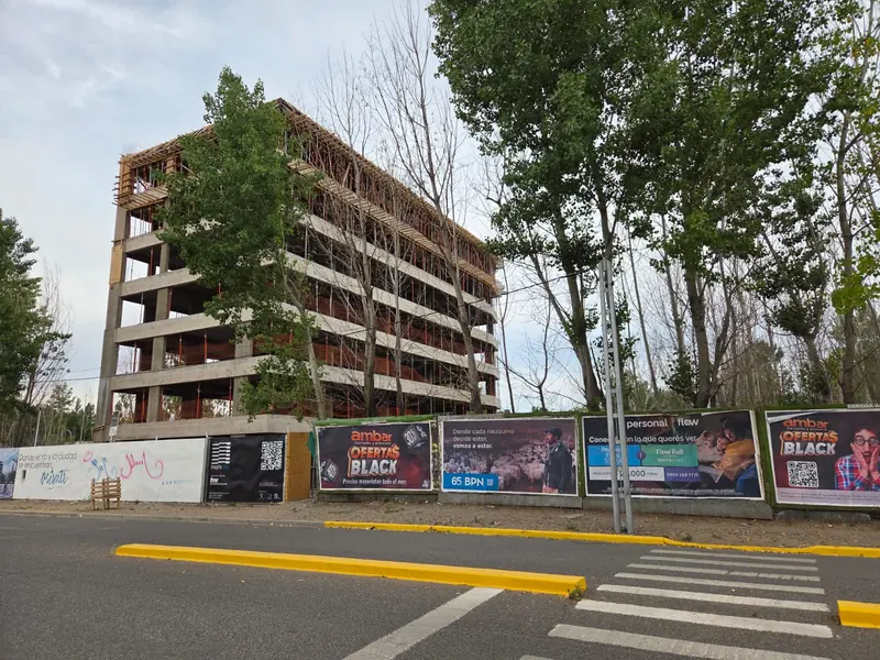 View of the building under construction from the street, with sidewalk and site hoarding
