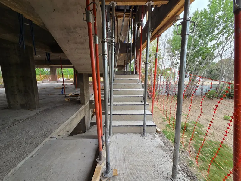 Completed concrete stair with steel props and orange barrier fencing