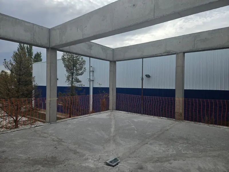 Espacio en obra con columnas y vigas de hormigón y piso de hormigón terminado