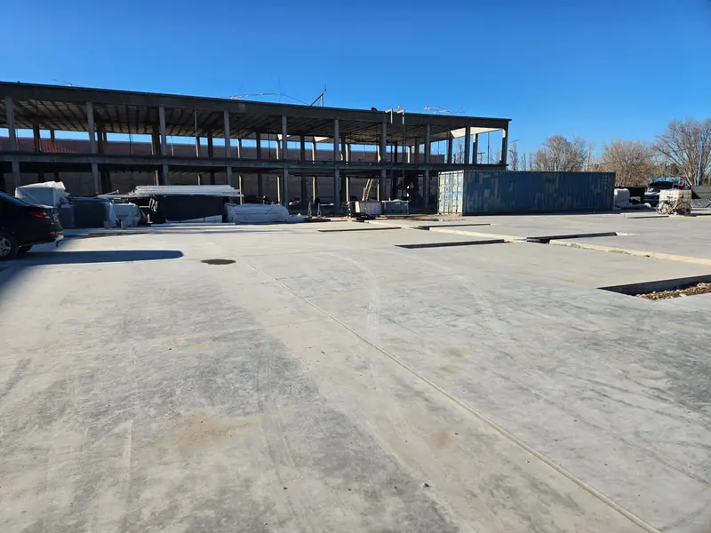 Playa de hormigón terminada en primer plano con la estructura del edificio al fondo