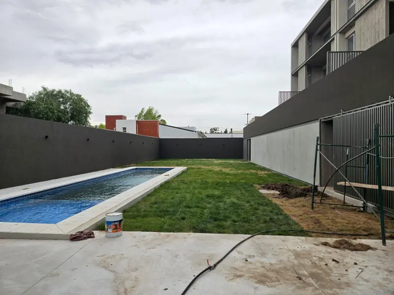 Finished rear courtyard with swimming pool, lawn and grey rendered walls