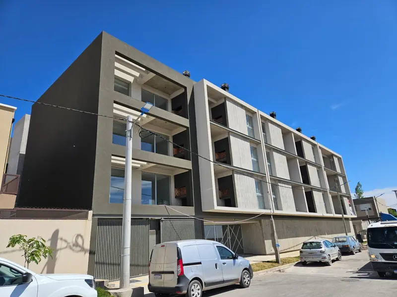 Finished facade of the three-storey building with balconies and grey render