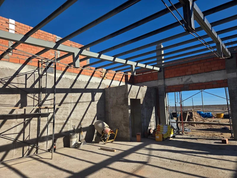 Estructura metalica del techo en montaje, con andamio y operario trabajando