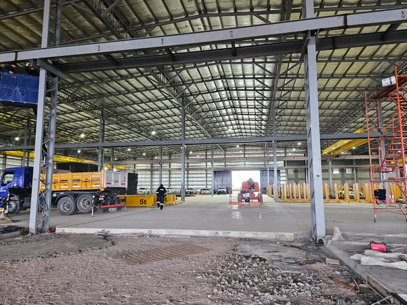 Interior of the industrial shed with steel structure, roof and trucks in the loading area