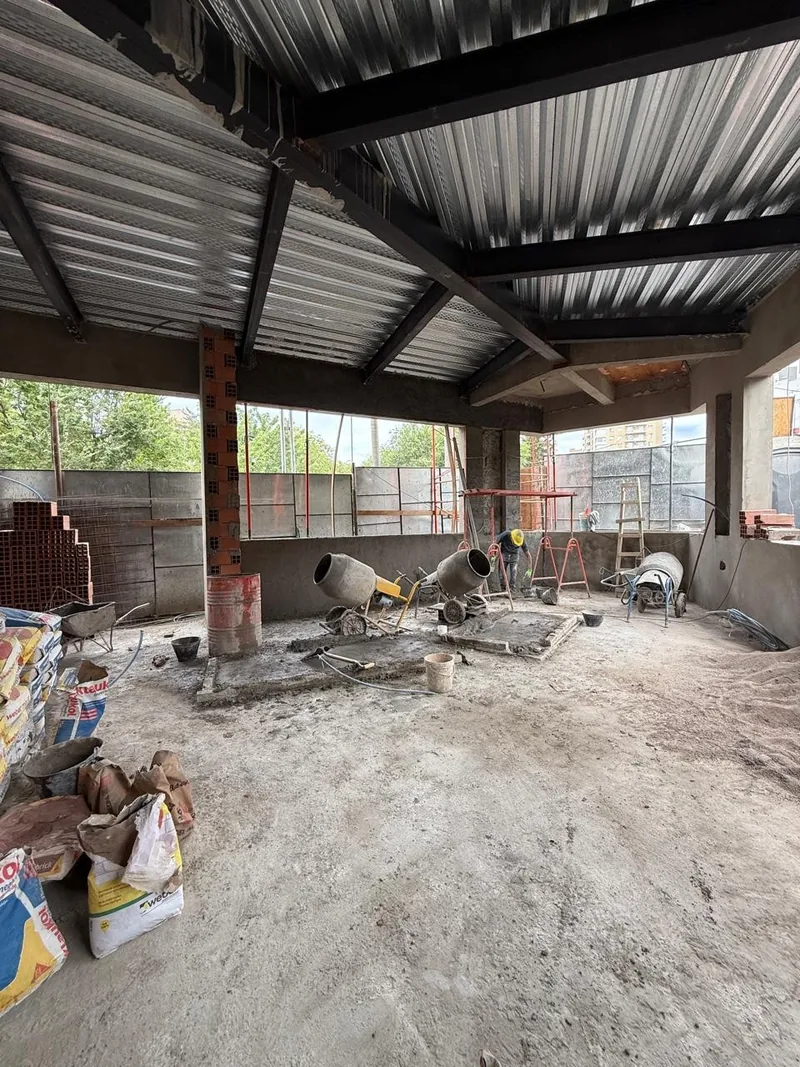 Interior en obra con la estructura metalica del techo y materiales acopiados