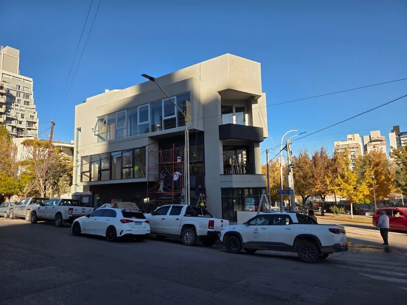 Edificio en construccion visto desde la calle, con vehiculos de la obra
