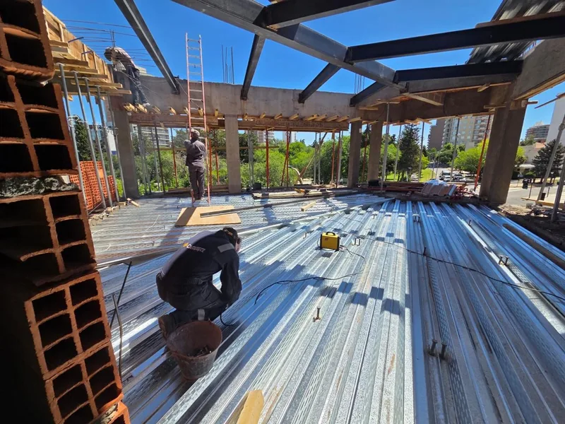 Estructura metalica del techo en montaje, con un operario trabajando