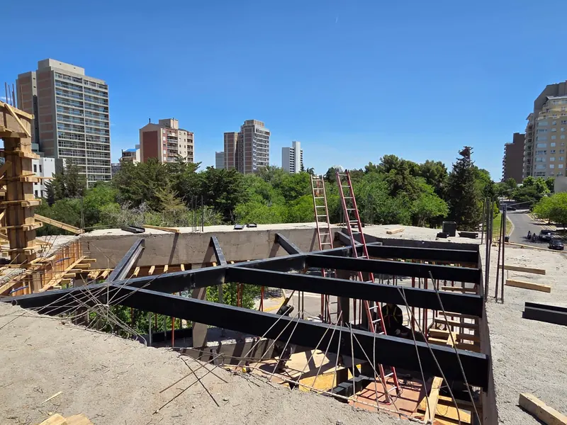 Steel beams erected on the concrete structure, with city tower blocks in the background