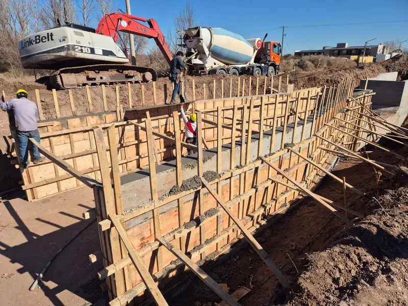 Concrete wall formwork with an excavator and concrete mixer truck on site