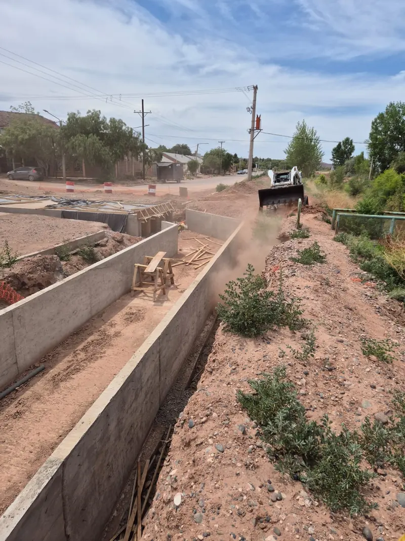 Finished concrete drainage channel running along a street in Añelo