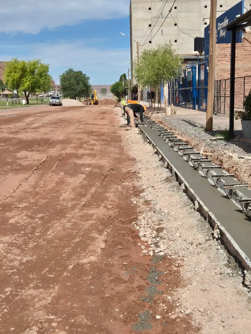 Freshly poured concrete curb and gutter on an unpaved street in Añelo