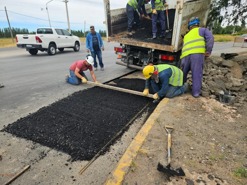 Cuadrilla de trabajo aplicando asfalto en una calle de tierra