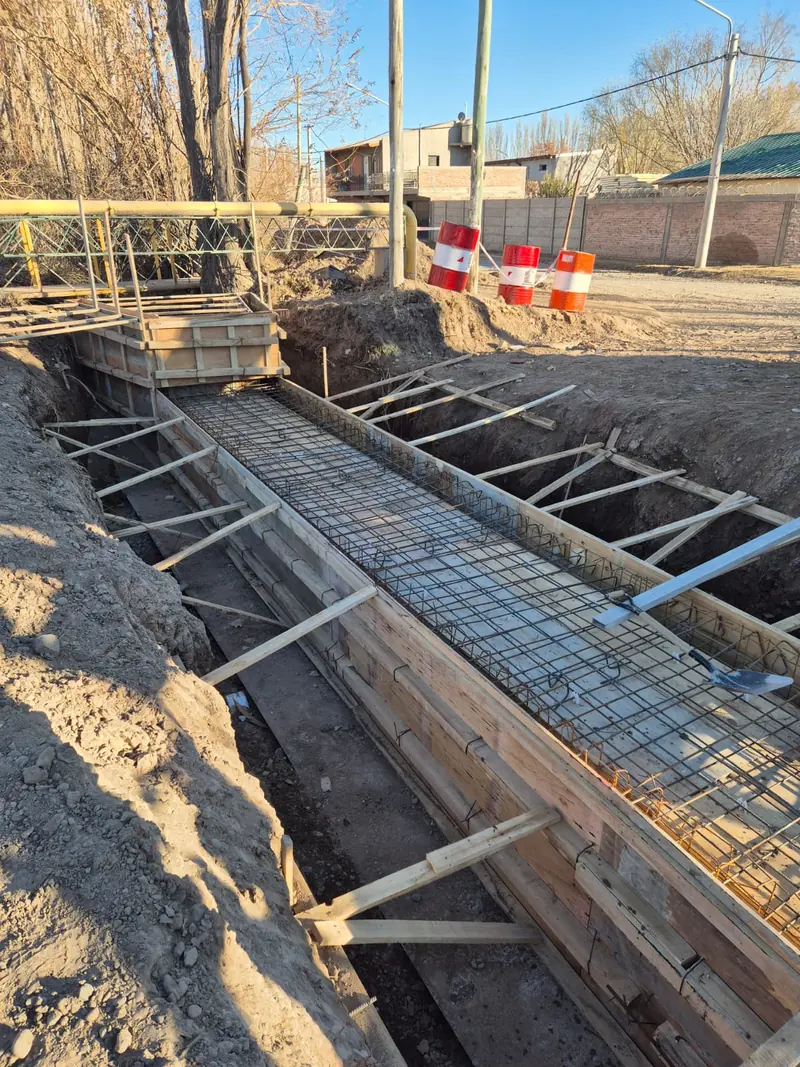 Trench with formwork and reinforcement for the conduit, next to the signed road