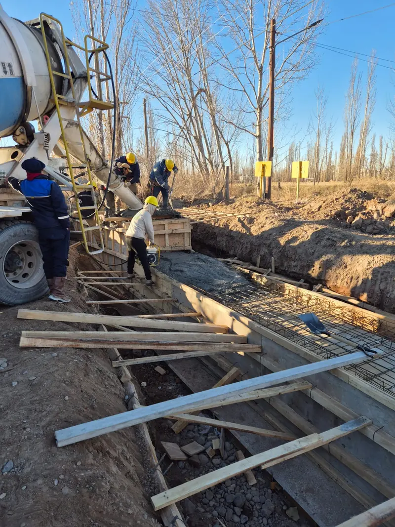 Concrete mixer truck discharging down the chute while the team works the concrete