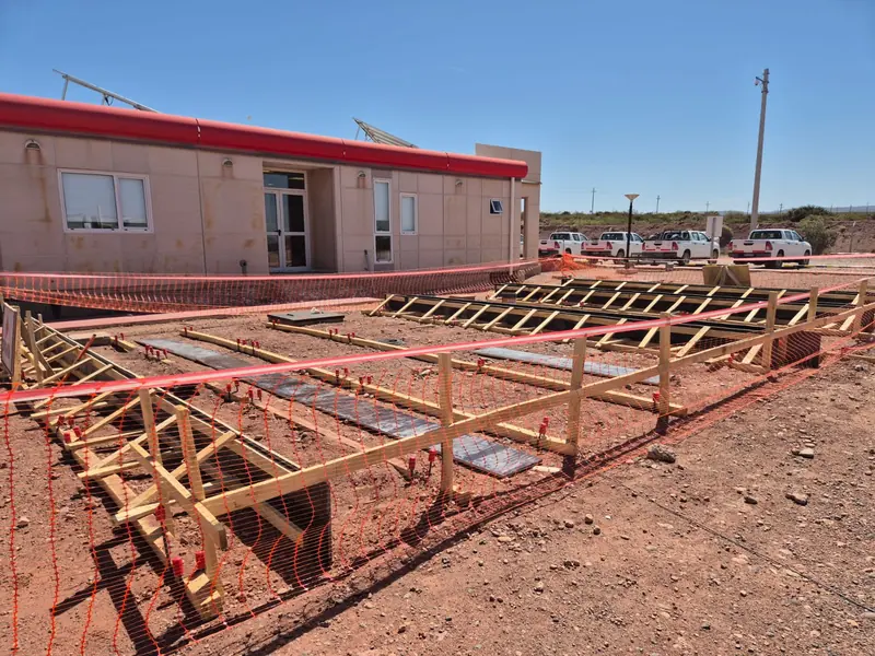 Timber formwork for ground beams with orange fencing beside the operations building