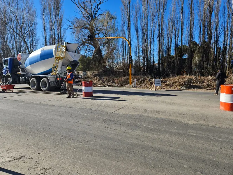 Camión hormigonero descargando sobre la calzada con cuadrilla señalizada