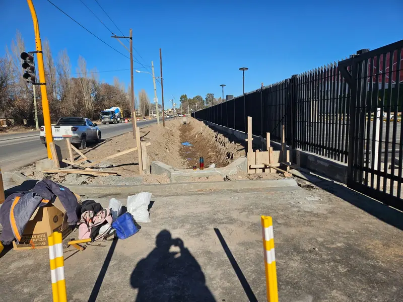 Encofrado de cordón y vereda junto al cerco perimetral metálico del predio