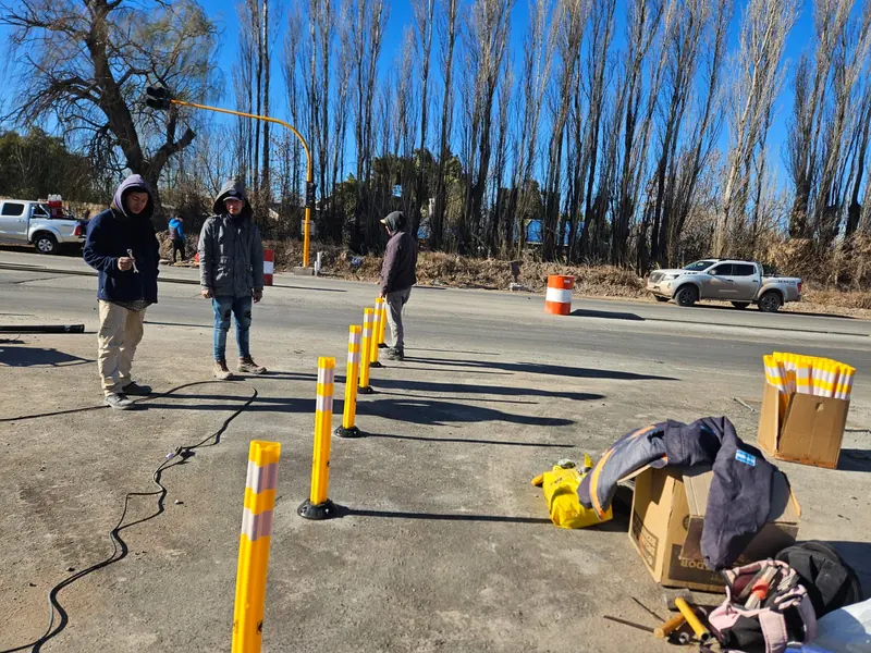 Operarios colocando defensas viales amarillas sobre el pavimento