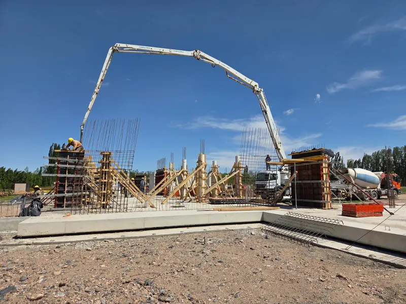 Concrete boom pump with its boom extended over the structure under construction