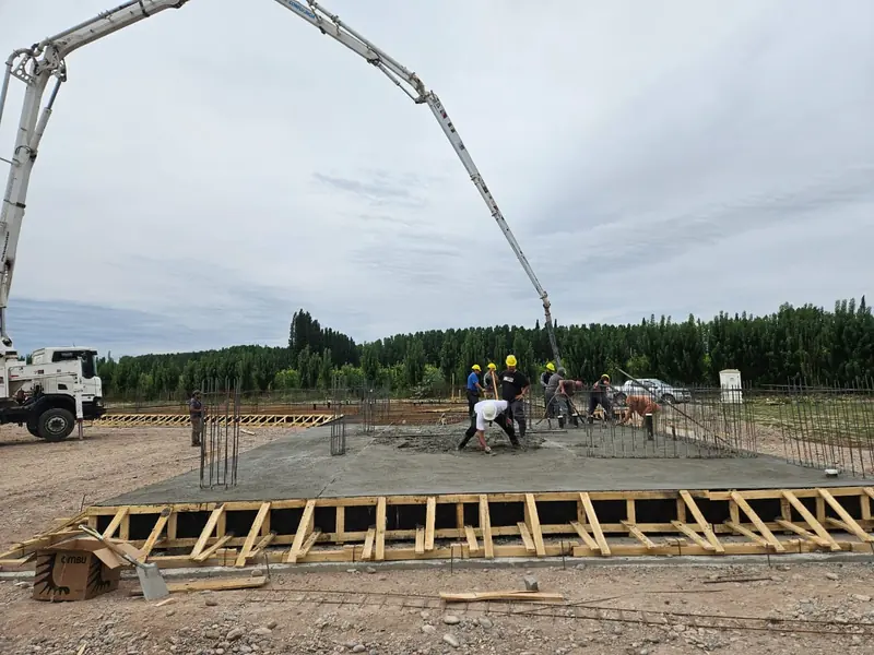 Crew screeding the fresh concrete of the raft slab next to the boom pump
