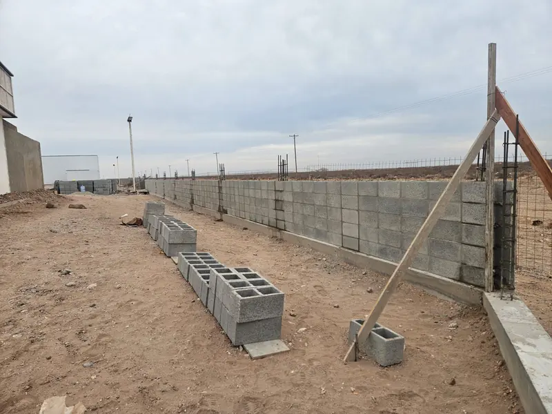 Muro perimetral de bloques de hormigón en construcción con puntales de madera