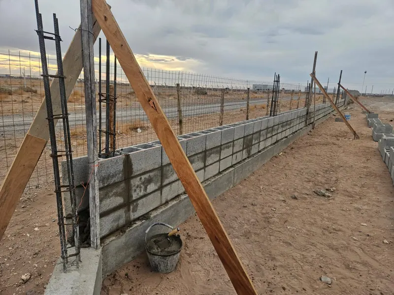 Muro perimetral de bloques de hormigón junto al cerco de alambre al atardecer