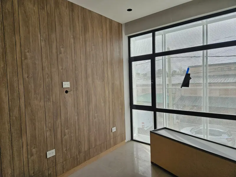 Office interior with a timber-clad wall and finished black aluminium window