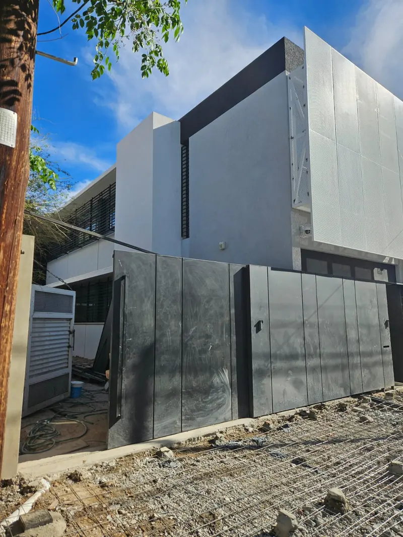 Side facade of the building with grey panels and a sliding metal gate