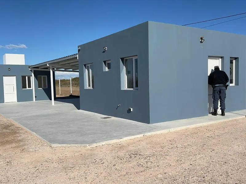Lateral del edificio terminado con vereda de hormigón y carpinterías colocadas