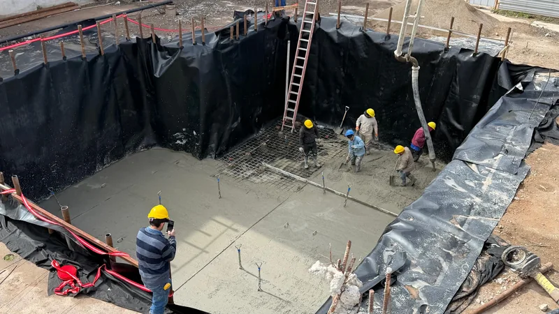 Operarios trabajando en la platea de hormigon dentro de la excavacion