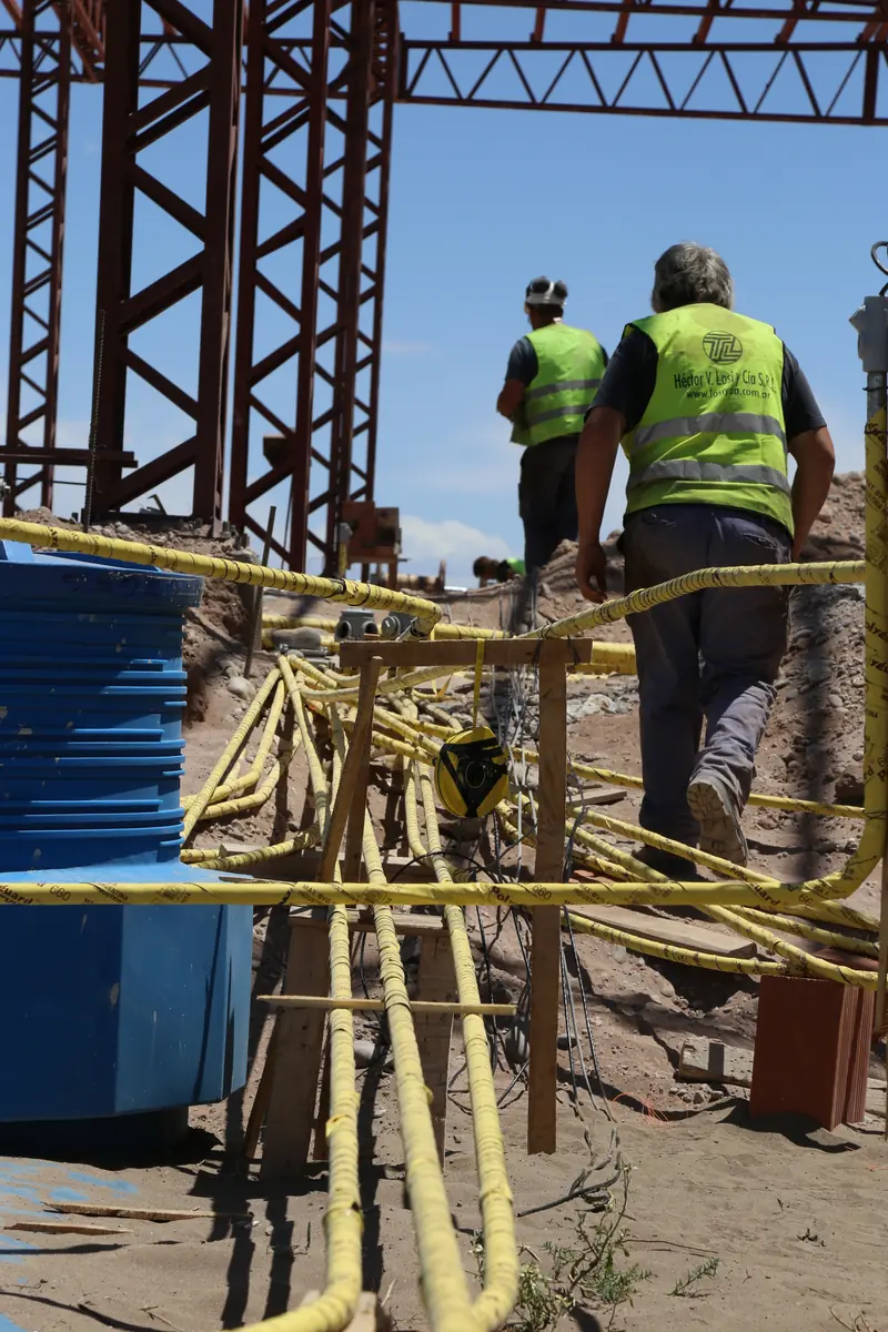 Operarios junto al tendido de cañerías y la estructura metálica de la marquesina