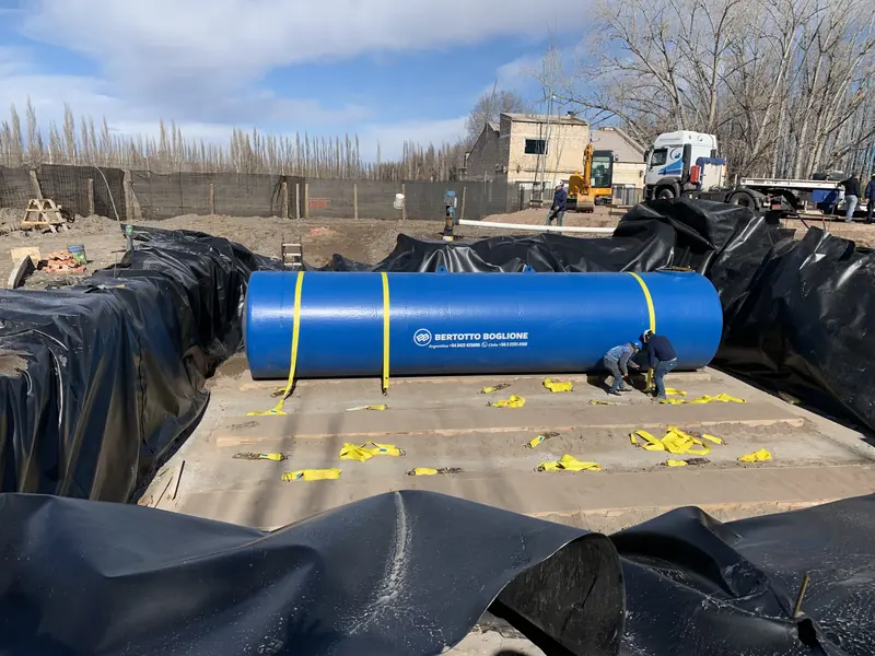 Tanque de combustible cilíndrico azul apoyado sobre la excavación impermeabilizada antes de enterrarlo