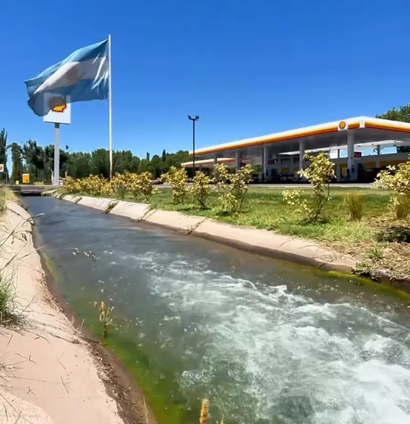Estación de servicio Shell terminada junto a un canal de riego, con mástil y bandera argentina