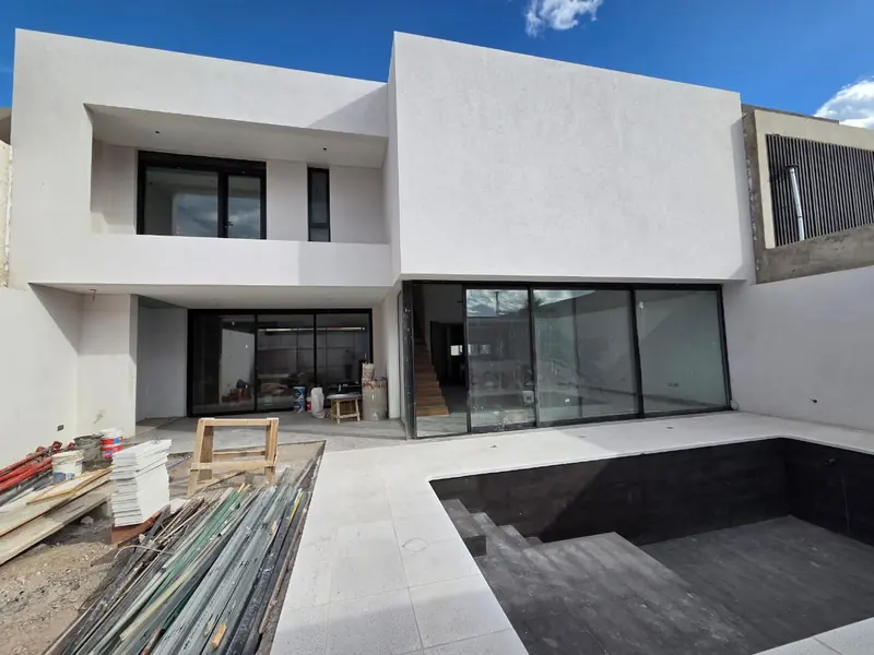 Rear elevation of the house with large black windows and pool under construction