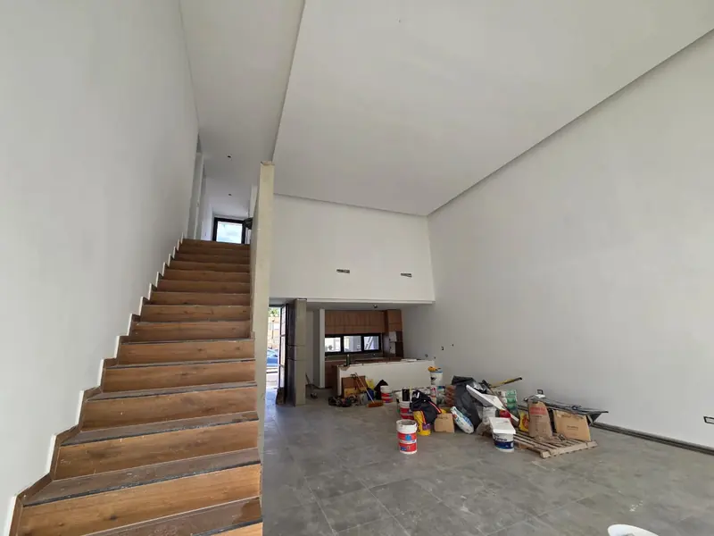 Timber staircase and double-height space with walls finished in white