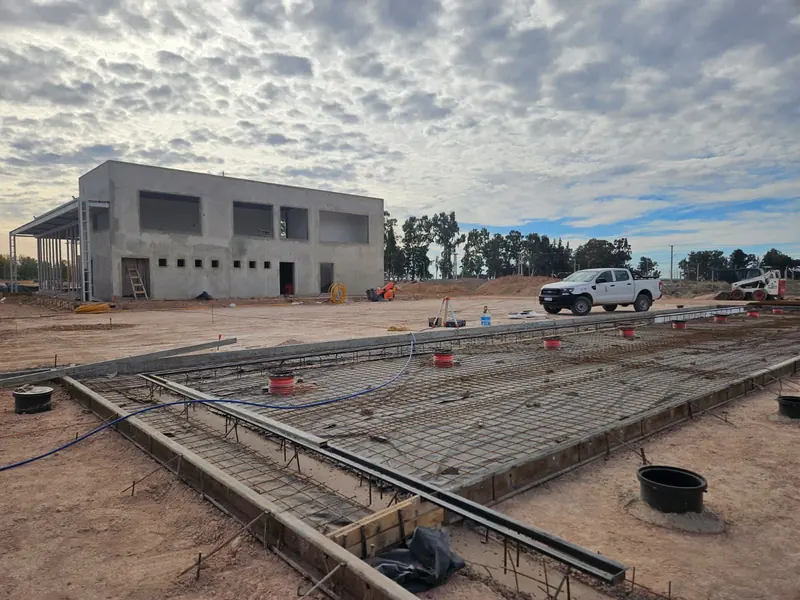 Two-storey concrete building under construction with raft slab reinforcement in the foreground