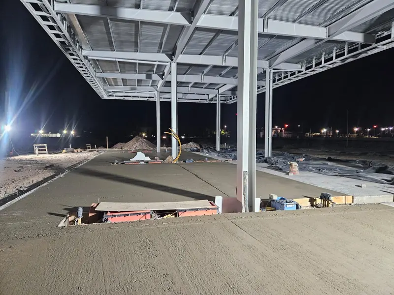 Night-time forecourt concrete pour under the lit canopy